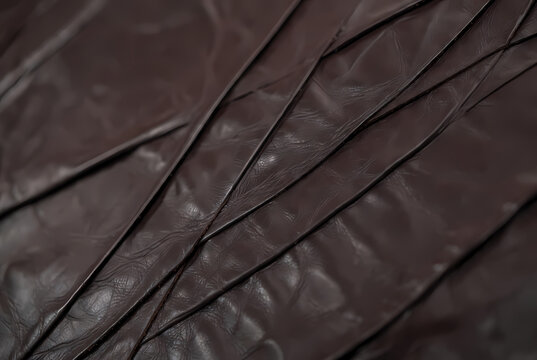 A close-up view of a dark brown leather texture with deep creases and folds