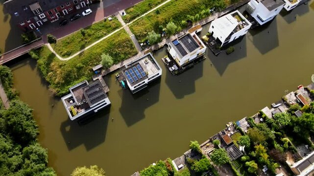 Aerial view of modern floating houses with solar panels along a canal in Delft, South Holland, Netherlands.