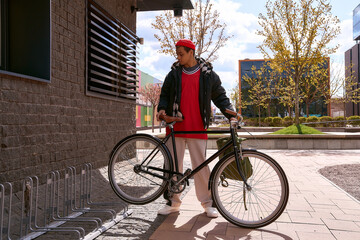 Obraz premium Handsome young man in stylish attire enjoys the city with his bicycle under a bright sky