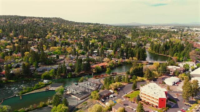 Drone follows a river through a compact city revealing buildings parks and greenery along its winding banks