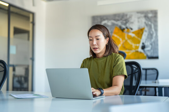 Asian businesswoman working on laptop in modern office
