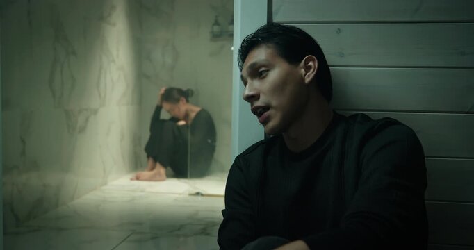 Depressed man sitting near bathroom wall, sad woman cry inside shower bath room. Couple quarrel ignoring problem. Relationship crisis, misunderstanding, loneliness concept. Family conflict break up.