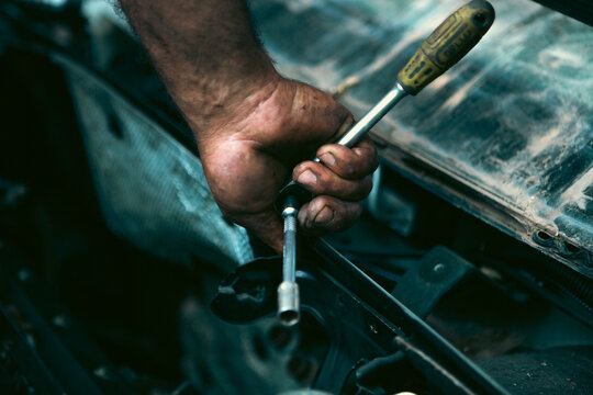 Auto mechanic working in auto repair service. Close-up of hand with screwdriver