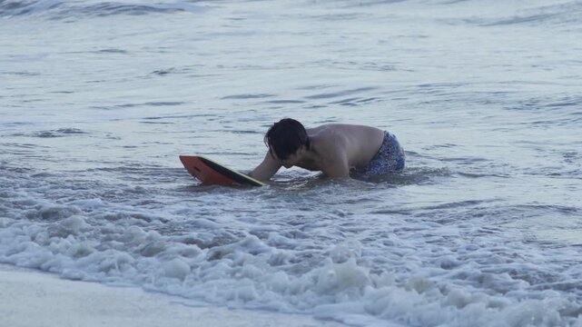 Footage of Young Man Bodyboarding on Ocean Waves During Summer Vacation. Ideal for Travel, Tourism, Beach Lifestyle, Adventure Sports, Outdoor Recreation, Tropical Destinations and Active lifestyle.