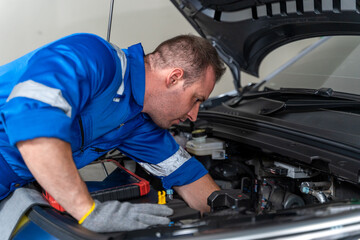 Fototapeta premium Electric Vehicle Mechanic Examining Engine Bay With Diagnostic Tool