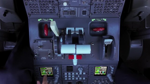 Overhead view inside a jet cockpit with a view of the hand of a veteran caucasian pilot adjusting the thrust levers in a real flight.