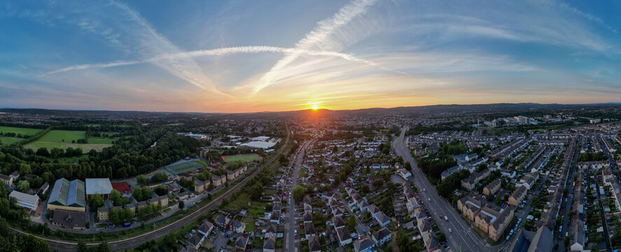 180&deg; Panoramic Aerial Drone Shot of Cardiff Cityscape Featuring North Road, River Taff, Railway, Parks, and Residential Areas Under Vibrant Sunset Sky, Cardiff, Wales, United Kingdom