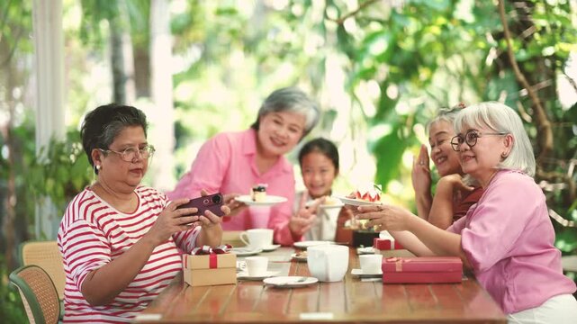 Happy older adults use smartphone to take photos and record memorable moments together. Friendship, healthy aging, social activities and digital lifestyle create meaningful experiences.