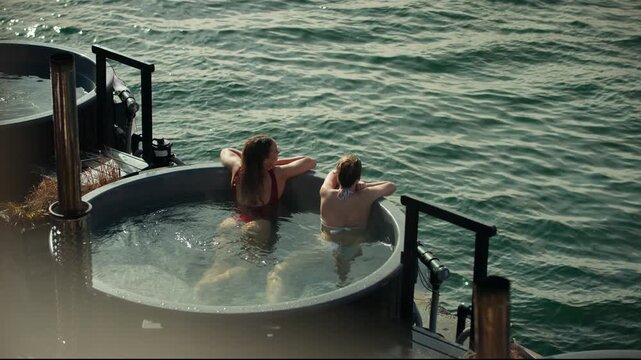 Women relaxing in outdoor hot tub during spa vacation retreat on open water