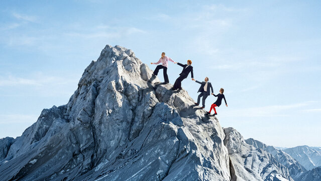 Business team climbing mountain together as teamwork and leadership challenge. Concept of team collaboration, strategic corporate success, business growth, overcoming obstacles.