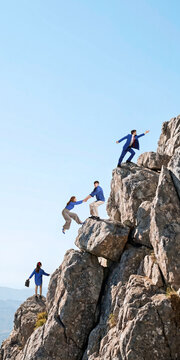 Business team helping colleague climb rocky mountain through teamwork and support. Concept of team collaboration, mutual support, leadership training, shared goals.