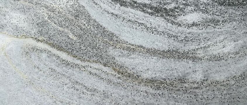 Natural foamy, marble-like patterns move slowly on the water's surface; an abstract natural background.