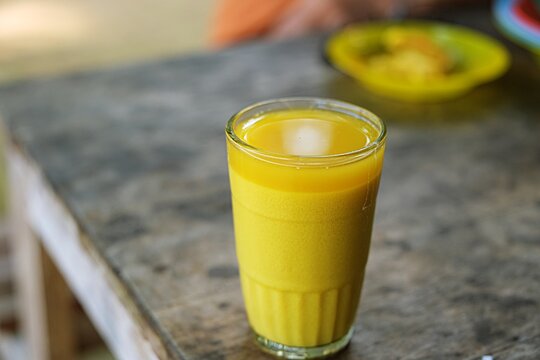Traditional Indonesian Herbal Jamu Drink in Glass.Healthy traditional Indonesian herbal jamu kunyit asem drink served in a glass with natural ingredients and wellness concept.