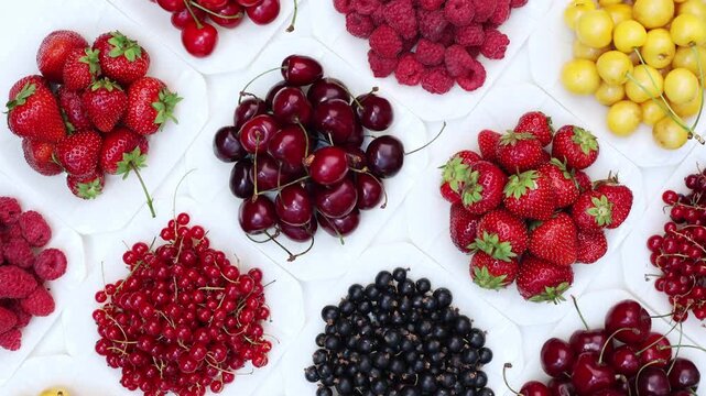 Colorful Summer Fruits and Berries Flat Lay Rotation Healthy Food Background. Fresh Strawberries Raspberries Currants and Cherries Rotating Top View Food Concept. Berry Composition in White Bowls Spin