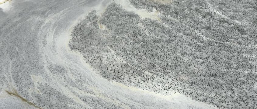 Natural foamy, marble-like patterns move slowly on the water's surface; an abstract natural background.