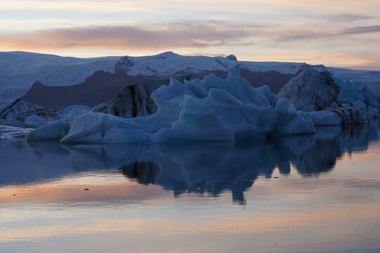 View of Jokulsarlon Glacier Lagoon with floating icebergs reflecting in the calm water at sunset in Hofn, Sveitarfelagid Hornafjordur, Iceland.