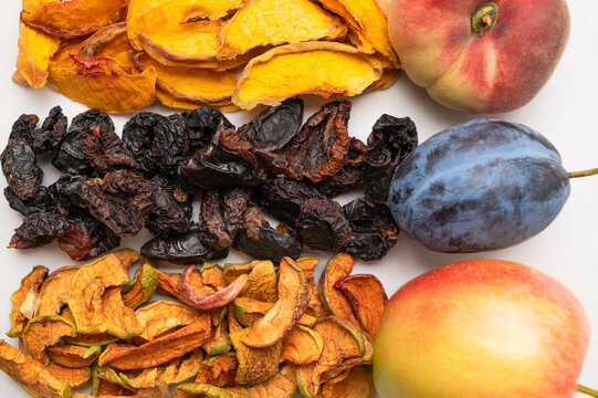 Fresh peach, plum, apple with matching dried fruits arranged in top view on light background. Fresh produce highlights healthy nutrition, wholesome ingredients, food branding and educational content.