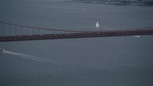 Golden Gate Bridge Roadway With Sailboat nearby In Bay On Overcast Day - Aerial Drone Shot