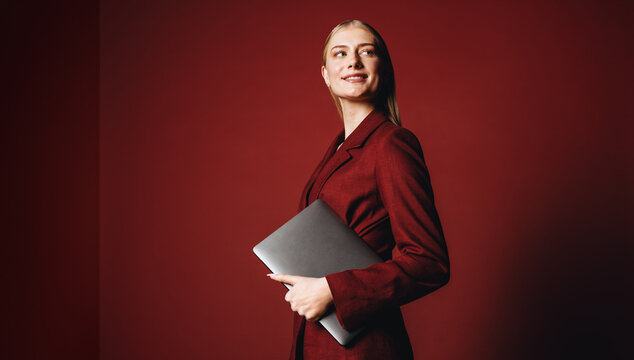 The business woman holds a laptop in a professional studio portrait