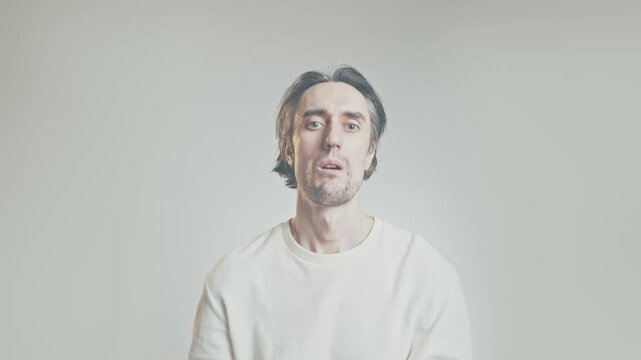 Young man mid-shot in minimal studio with gray-to-white gradient background, showing varied facial expressions and condescending thumbs up gesture, copy space