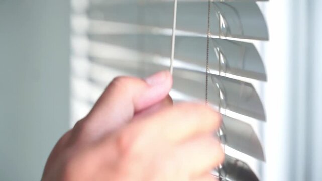 opening blinds to reveal a bright window. Indoor comfort, sunlight control, and contemporary home lifestyle theme.