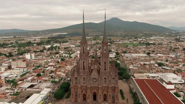 Aerial dolly in overlooking the iconic facade of the Sacred Heart Expiatory neo gothic temple and Zamora de Hidalgo cityscape