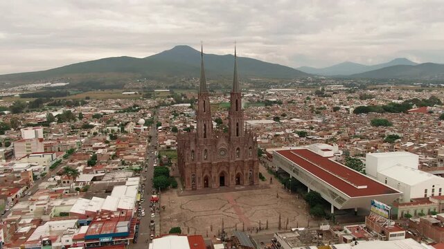 Aerial panpramic orbit of the iconic facade of the Sacred Heart Expiatory neo gothic temple and Zamora de Hidalgo cityscape