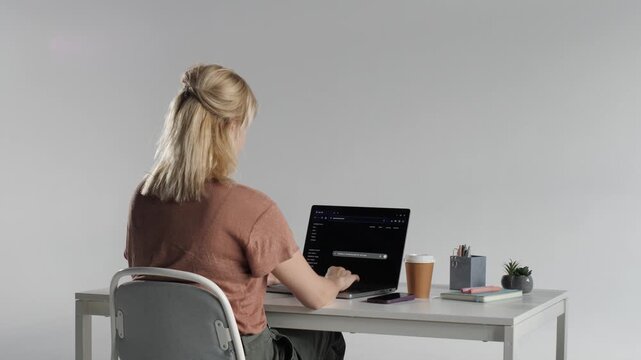 Woman stretching at desk while using ai tools on laptop