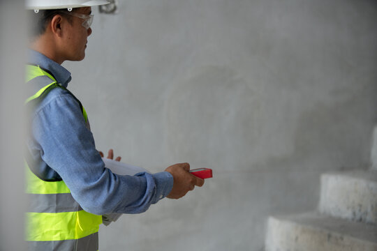 Construction professional evaluating a work site while wearing protective equipment and using technical tools during the project