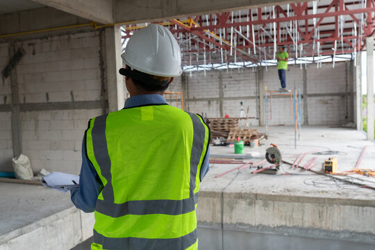 Construction professional monitoring site development alongside an engineer wearing safety equipment at a building project