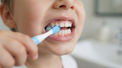 Fototapeta premium Extreme close-up of a child's teeth being brushed with a toothbrush, dental health and oral hygiene concept, clean mouth self-care routine