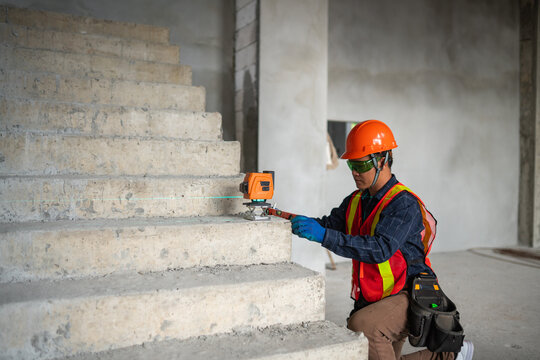 Construction professional measuring staircase with laser level in an industrial environment