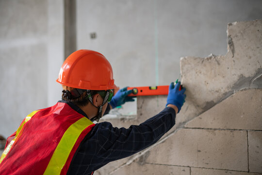 Construction worker using level tool for accurate measurements on building site in industrial setting