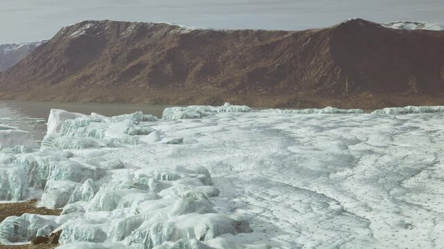 In a remote area, large glaciers are seen next to mountains. The landscape shows ice formations and rocky terrain under clear skies. This scene captures the beauty of nature.