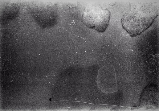 Blank grained film strip texture background with heavy grain, dust and light leak. Old expired soviet moldy photographic film scan. Black and white.