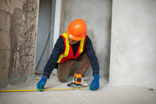 Construction professional using a laser level to measure the floor at a renovation site