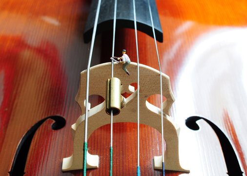 Miniaturarbeiter warten Violoncello-Steg &ndash; Kreatives Konzept f&uuml;r Instrumentenpflege und Musikhandwerk