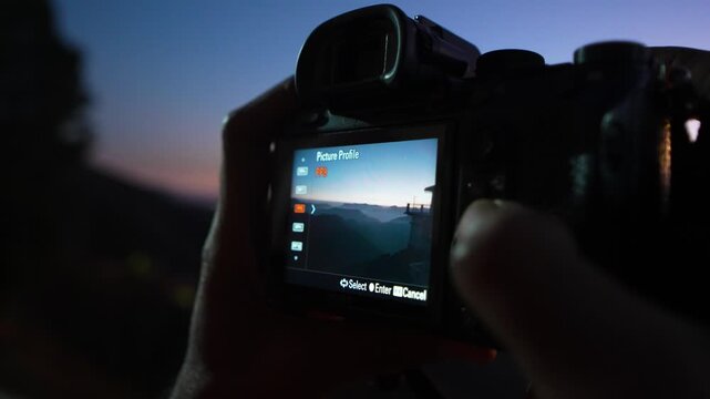 Close-up of a person capturing a sunset with a digital camera during twilight in a natural outdoor setting chakrata, dehradun, uttarakhand