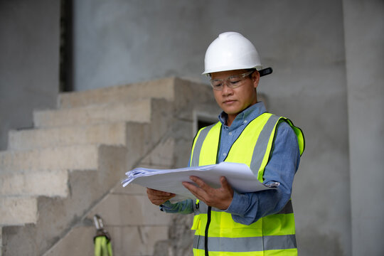 Construction professional examining blueprints on a job site for an upcoming building development