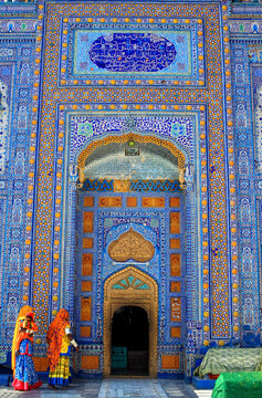 View of the intricate blue and yellow tile work at the Shrine of Sachal Sarmast with women in traditional clothing in Daraza Sharif, Sindh, Pakistan.