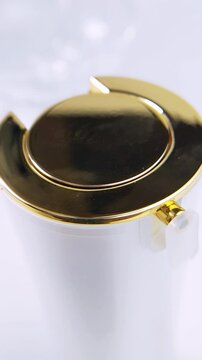 Top close up view of beauty product cap featuring white and gold decorative ornaments. Isolated on white background. Luxurious cosmetic packaging detail for premium skincare concept.