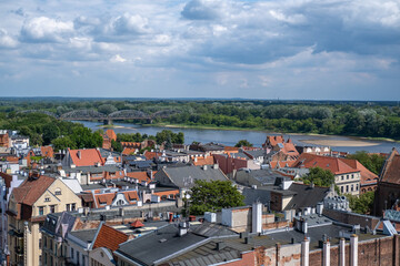 Obraz premium Scenic view over historic old town buildings in Torun towards the Jozef Pilsudski steel truss bridge crossing the Vistula River.
