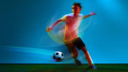Naklejka premium Soccer player controlling football with colorful motion blur on illuminated field. Concept of football training, sports equipment ads, youth academy promotion, athletic performance, sports branding.