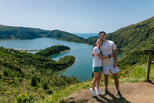 Happy couple standing together on a mountain path during a hike overlooking a lake