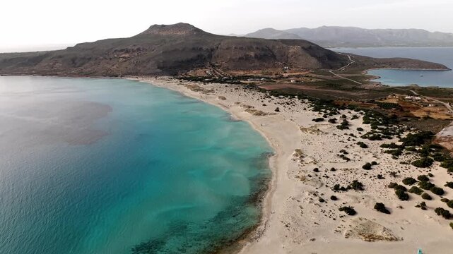 Simos beach glowing sea floor on Elafonisos island at sunset, coastal sand dunes, sea cedar forests, rocky limestone hills and salt marshes, Panoramic aerial view