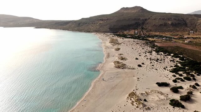 Simos beach on Elafonisos island at sunset, coastal sand dunes, sea cedar forests, rocky limestone hills and salt marshes, Panoramic drone view