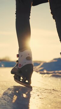 A person is ice skating on a smooth surface while wearing ice skates. The sun is setting, casting a warm glow over the skating scene and the ice beneath the skater.