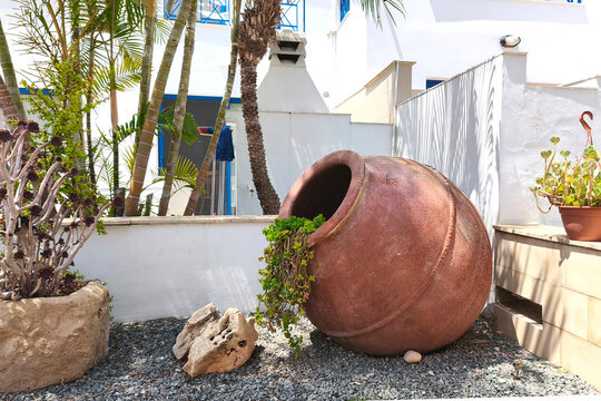 Traditional clay amphora planter in a landscaped courtyard of a Mediterranean resort in Protaras, Cyprus. Decorative garden with tropical plants, succulents and white architecture