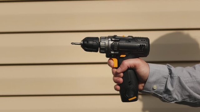Electric screwdriver. House wall. Turn on the screwdriver. Slow motion video. High quality 4k footage