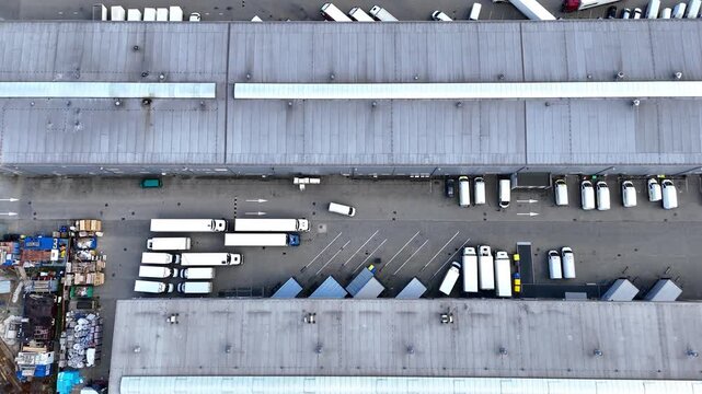 Aerial view of logistics warehouse with trucks parked in designated areas, showcasing organized loading zones and efficient space utilization in a commercial transport facility